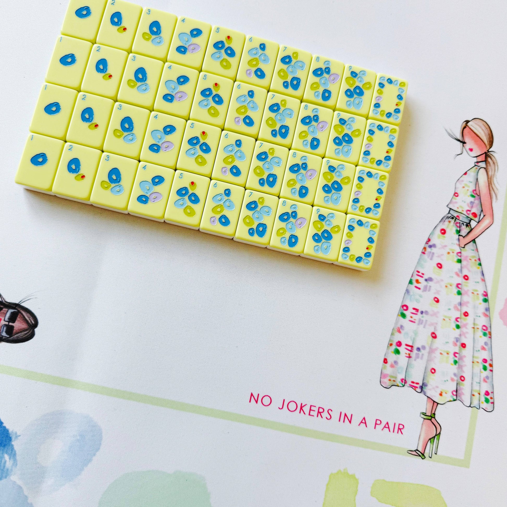 Pack of colorful dice with floral design on a white surface with a fashion illustration.