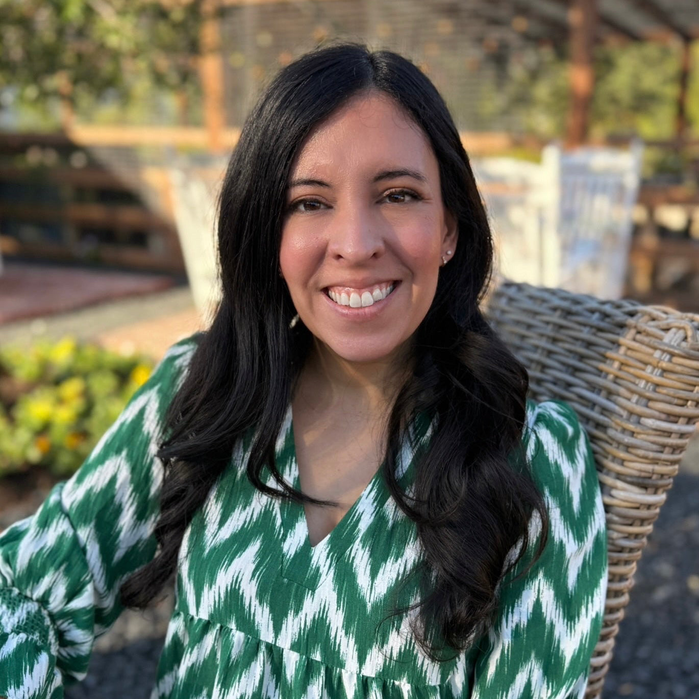 Woman in a green and white patterned dress sitting outdoors