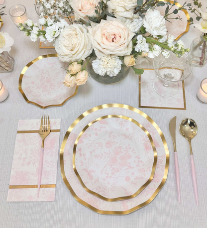 Elegant table setting with gold-rimmed plates, white flowers, and pink napkins. Wedding, shower, dinner party 