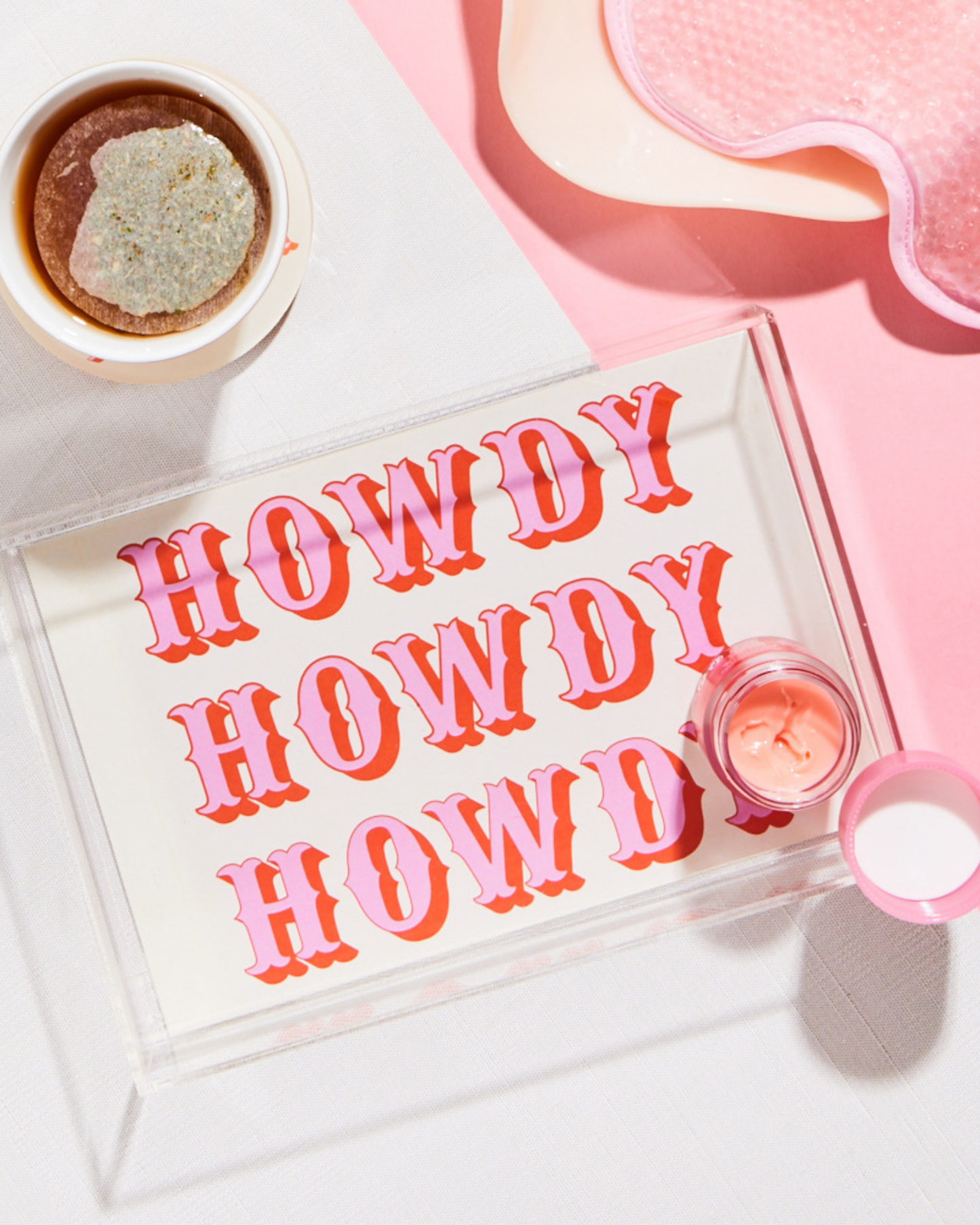 Acrylic jewelry tray with 'HOWDY' text on a pink background