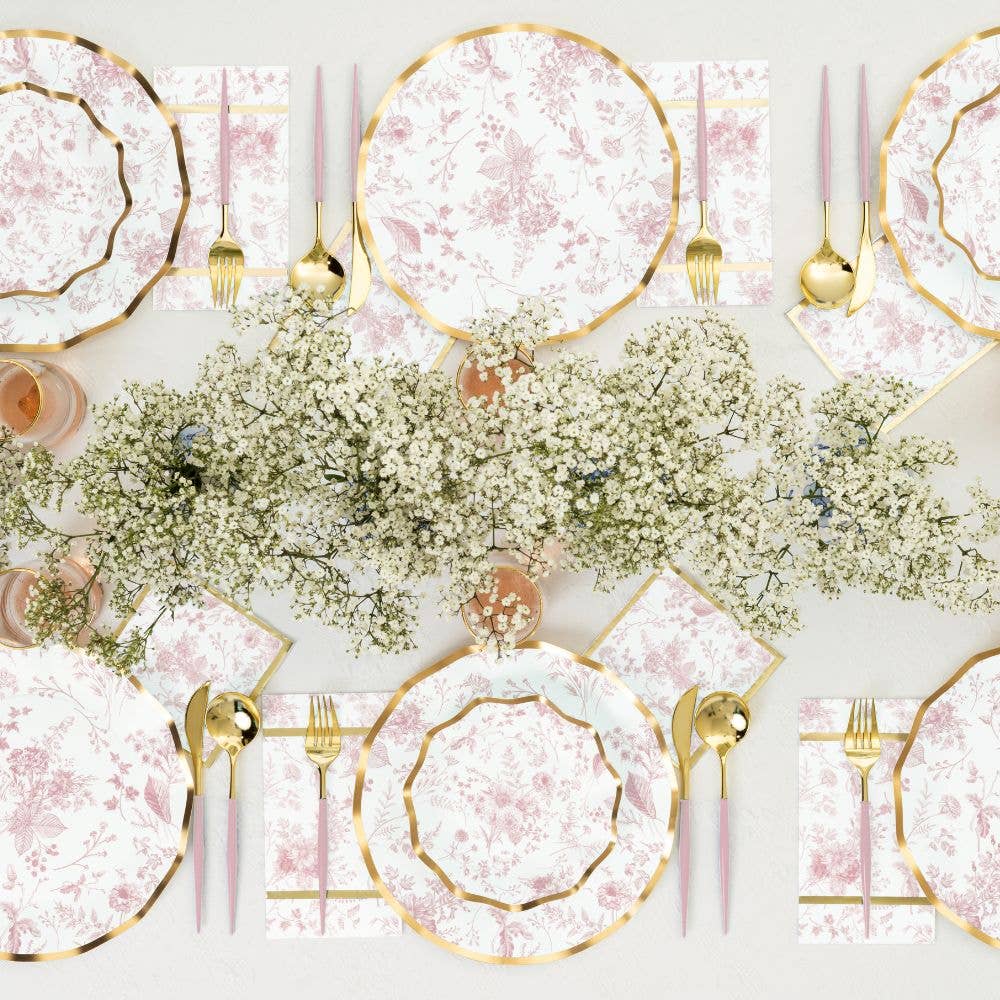 Elegant table setting with pink and gold plates, silverware, and floral centerpieces. For baby shower or bridal shower
