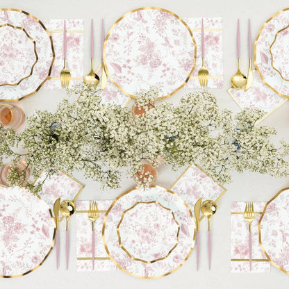 Elegant table setting with pink and gold plates, silverware, and floral centerpieces. For baby shower or bridal shower