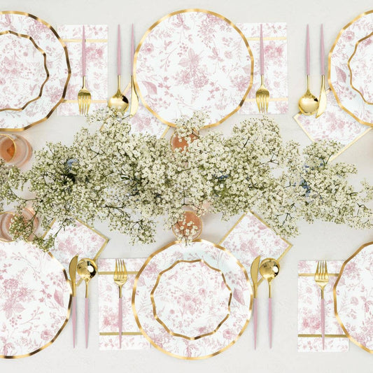 Elegant table setting with pink and gold plates, silverware, and floral centerpieces. For baby shower or bridal shower