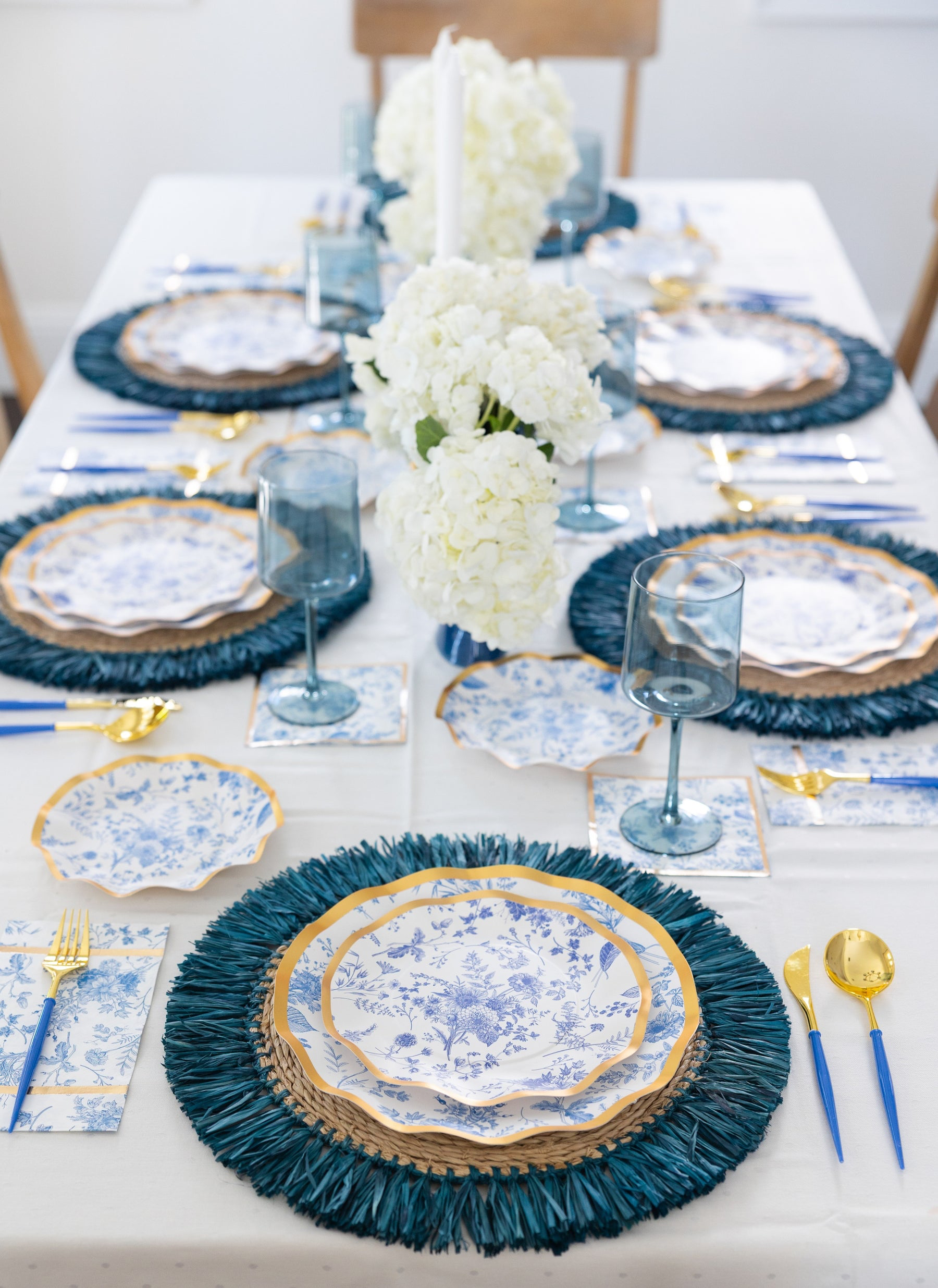 Elegant table setting with blue and white plates, napkins, and centerpieces.