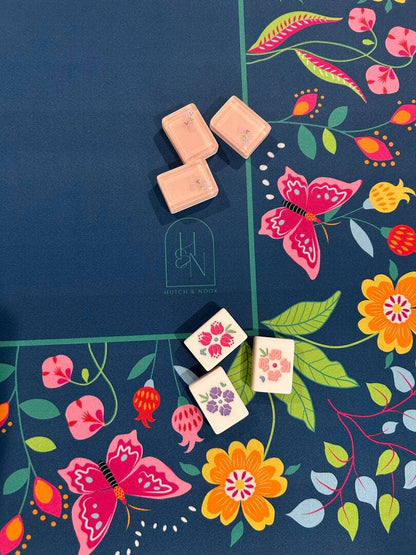 Decorative mahjong tiles with floral and butterfly designs on a colorful mahjong mat